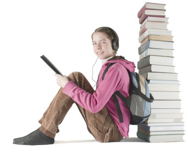 Teen girl reads ebook sitting near the stack of printed books clipart