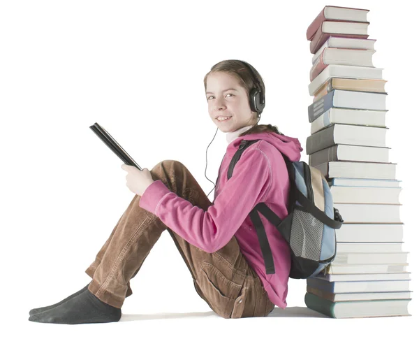 Teen girl reads ebook sitting near the stack of printed books — Stock Photo, Image