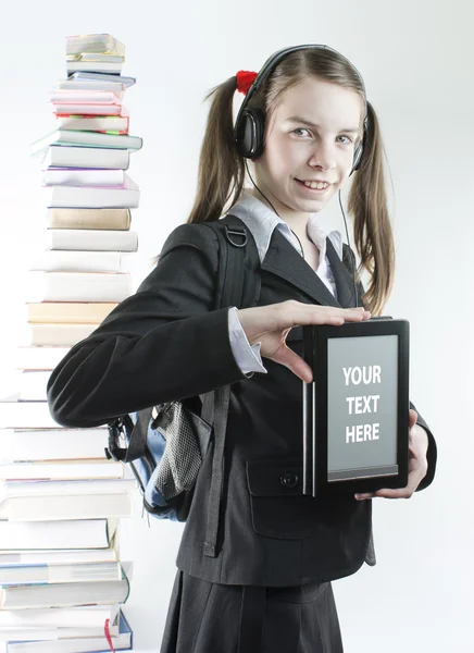 Tiener meisje met elektronische boek met een stapel van gedrukte boeken achter — Stockfoto