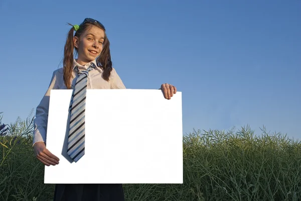 Έφηβος κοπέλα που κρατά αφίσα λευκό στο πράσινο πεδίο — Φωτογραφία Αρχείου
