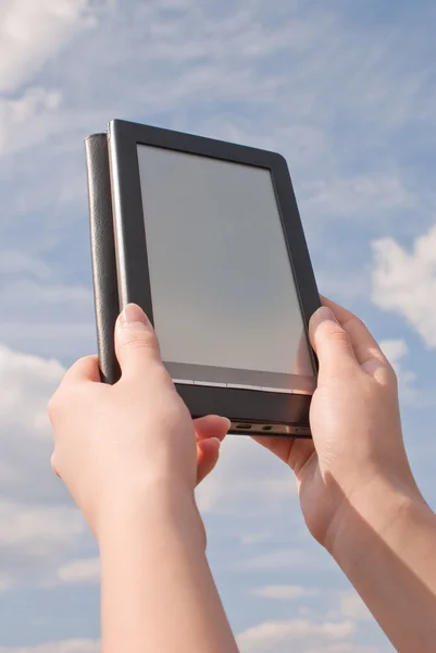 Las manos sostienen el lector electrónico de libros contra el cielo azul — Foto de Stock