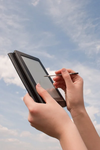 Tangan memegang buku elektronik pembaca terhadap langit biru — Stok Foto