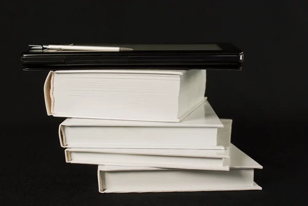 Stapel gedruckter Bücher mit elektronischem Lesegerät auf schwarzem Hintergrund — Stockfoto