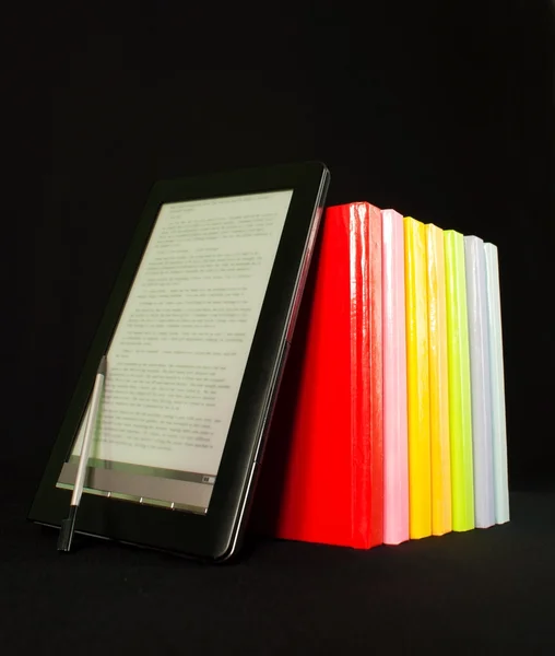 Fila de libros coloridos y lector de libros electrónicos en el fondo negro — Foto de Stock