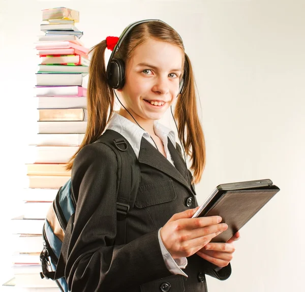Chica adolescente con libro electrónico con una pila de libros impresos detrás —  Fotos de Stock