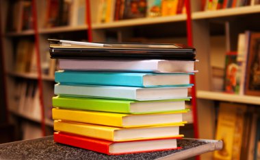 Stack of colorful books with electronic book reader clipart