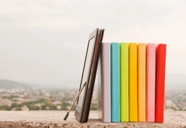 Fila de livros coloridos com leitor de livros eletrônicos — Fotografia de Stock