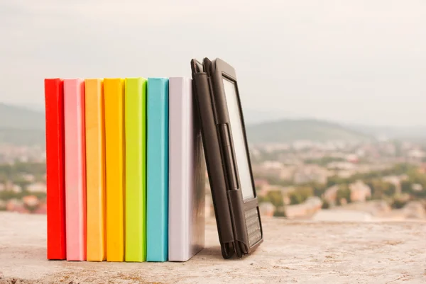 Fila di libri colorati con lettore di libri elettronico — Foto Stock