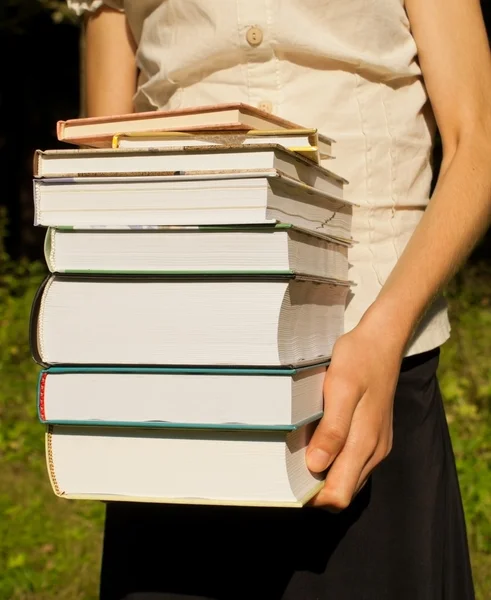 Genç kız bir kitap yığını tutan — Stok fotoğraf