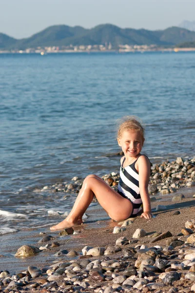 Güzel kız sahilde oturuyor. — Stok fotoğraf