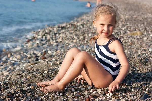 美しい女の子がビーチに座っていて — ストック写真