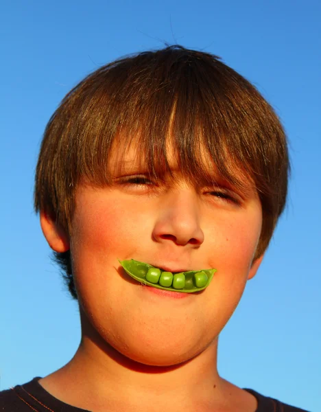エンドウ豆の鞘と笑った男の子 — ストック写真