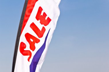 Sale flag flying against blue sky clipart