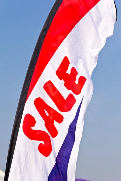 Prodej vlajka letí proti modré obloze — Stock fotografie