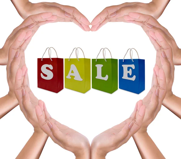 Försäljning etikett på shopping väska i händerna hjärtat — Stockfoto