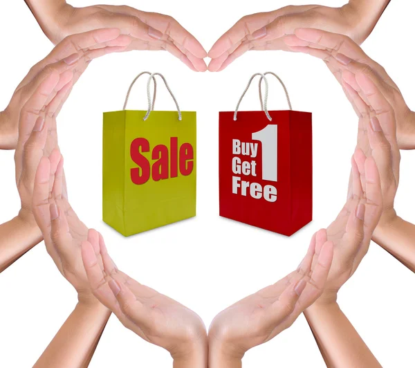 Försäljning etikett på shopping papper påse i handen hjärta — Stockfoto
