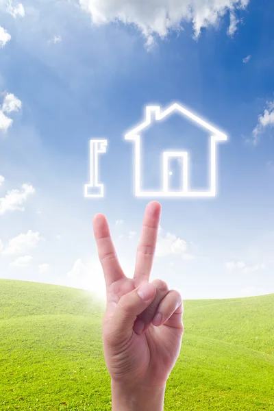 Hand pointing to key and house icon — Stock Photo, Image