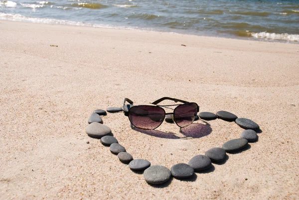 Heart from stones and sunglasses on the beach — Stock Photo, Image