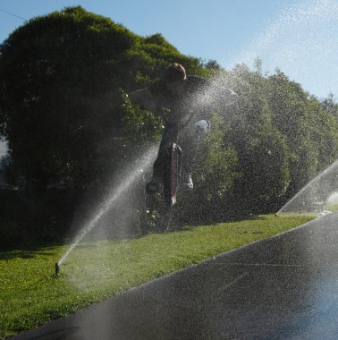 Boy jumping through fountain on bmx clipart