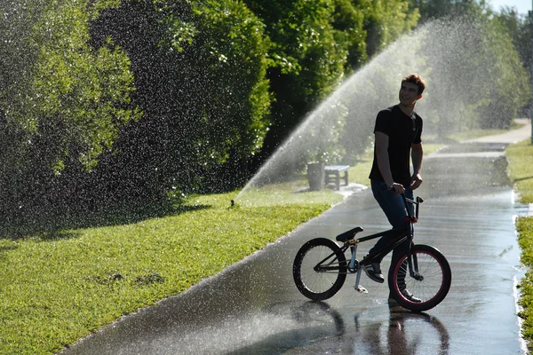 Chlapec s bmx pobytu na fontáně šplouchání pozadí — Stock fotografie