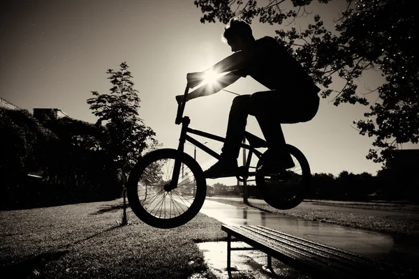 Boy jumping over bench on bmx Stock Image