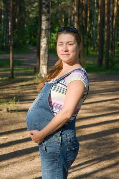 公園を散歩する妊娠中の女性。晴れた日の午後 — ストック写真