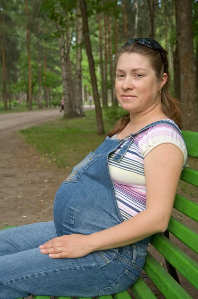 Gravid kvinna avkopplande på en parkbänk. — Stockfoto