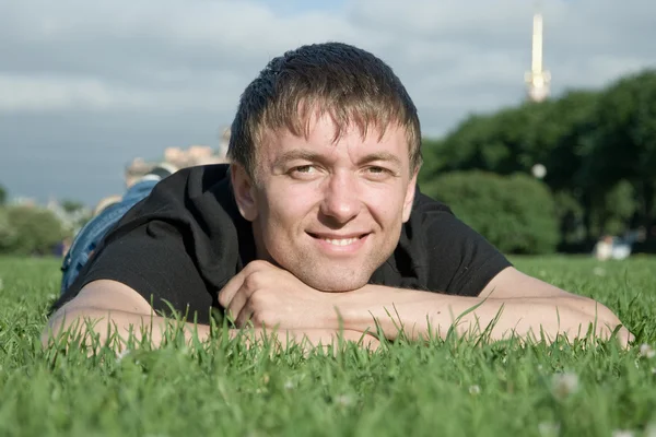 A young man lies not in the park grass — Stock Photo, Image