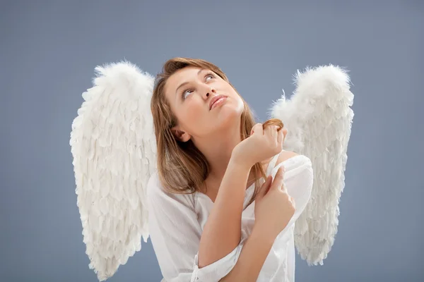 Schöner blonder Engel vor grauem Hintergrund — Stockfoto