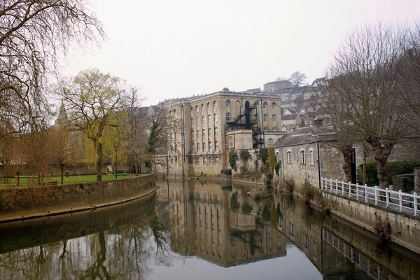 Oud gebouw en het park langs de kant van een rivier — Stockfoto