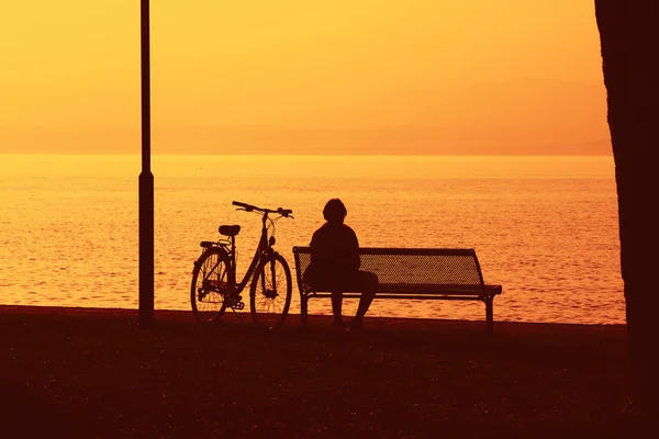Silhouette di signora e bici guardando verso il mare — Foto Stock
