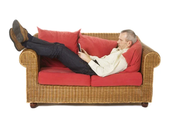 Man på en soffa med en e-läsare. Stockbild