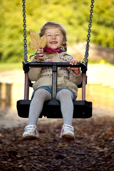 Маленька щаслива дівчинка на гойдалках — стокове фото