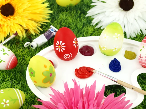 Цветы и пасхальные яйца на палитре — стоковое фото