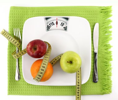 Diet concept. Fruits with measuring tape on a plate like weight scale clipart