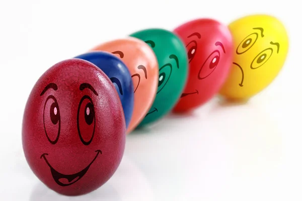 Huevos de Pascua de colores con caras divertidas dibujadas en una fila — Foto de Stock