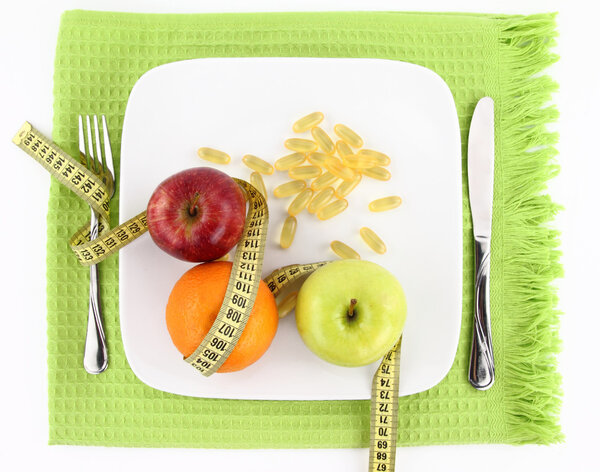 Fruits and vitamins with measuring tape on a plate