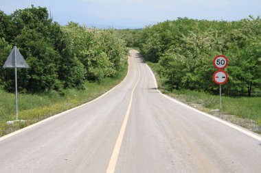 Winding country road with speed limit sign clipart