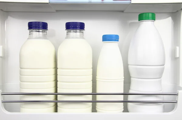 Olika flaskor av mjölk i kylen — Stockfoto