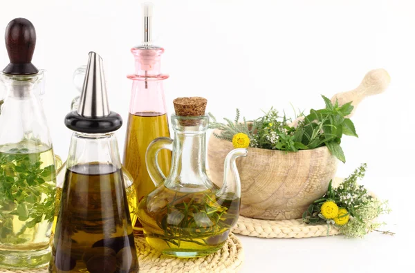 Argamassa e pilão com ervas e garrafas de azeite — Fotografia de Stock