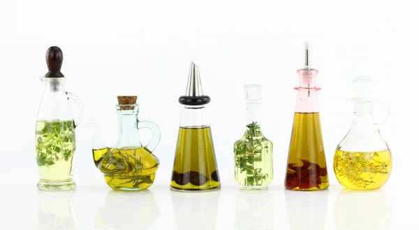 Різні пляшки оливкової олії з травами всередині — стокове фото
