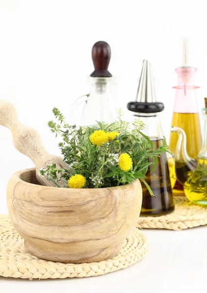 Mortero y mortero con hierbas y botellas de aceite de oliva — Foto de Stock