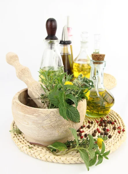 Mortar and pestle with herbs and bottles of olive oil — Stock Photo, Image