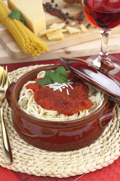 Spaghetti pasta with tomato sauce, cheese and basil in a clay pot — Stock Photo, Image