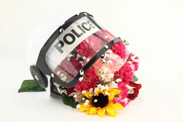 Casco de policía y flores. Un concepto contra la violencia —  Fotos de Stock