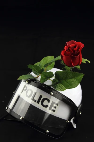 Capacete da polícia e rosa. Um conceito contra a violência — Fotografia de Stock