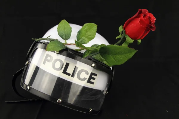 Casco della polizia e rosa. Un concetto contro la violenza — Foto Stock