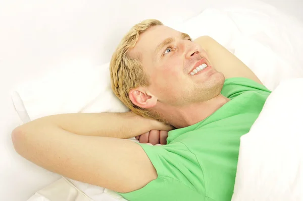 Cheerful young guy waking up in morning on bed — Stock Photo, Image