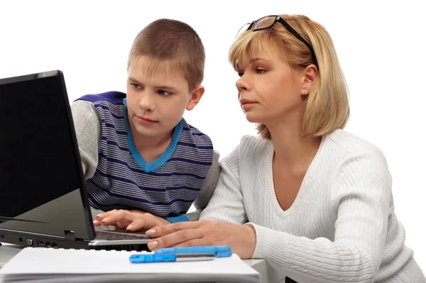 Портрет дорослої жінки, яка дивиться, як її син робить домашнє завдання — стокове фото