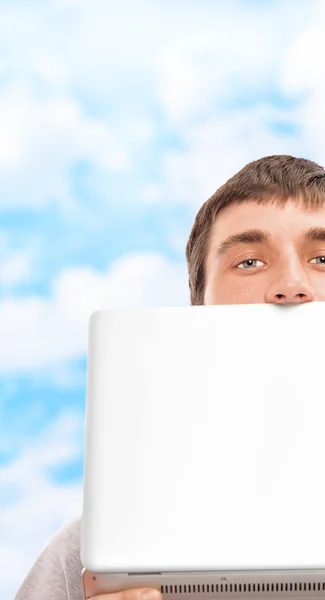 Молодий чоловік тримає ноутбук біля обличчя на відкритому повітрі — стокове фото